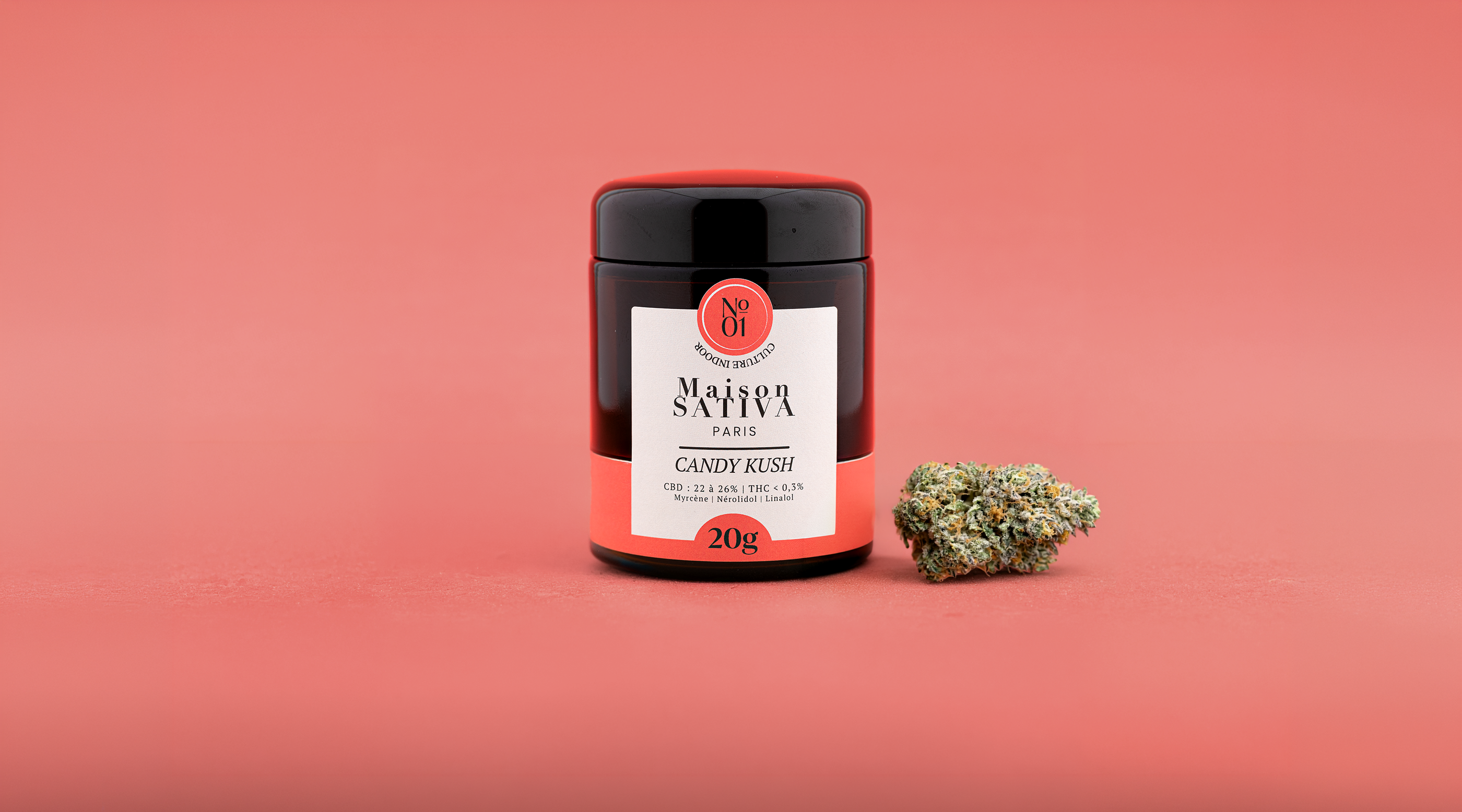Pot en verre de fleurs de CBD Candy Kush 20g Maison Sativa Paris avec une sommité florale de culture indoor à côté.