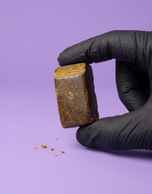 Petit bloc de résine Static Hash CBD tenu par une main avec un gant noir, illustrant sa compacité