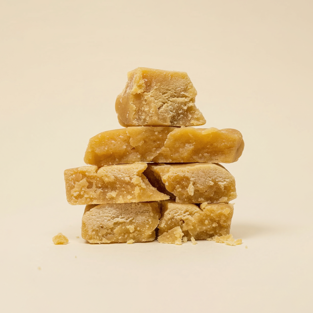 Morceaux de résine CBD Ice O Lator Mango empilés en pyramide, démontrant la consistance grasse et la texture effritable du hash.