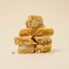 Morceaux de résine CBD Ice O Lator Mango empilés en pyramide, démontrant la consistance grasse et la texture effritable du hash.