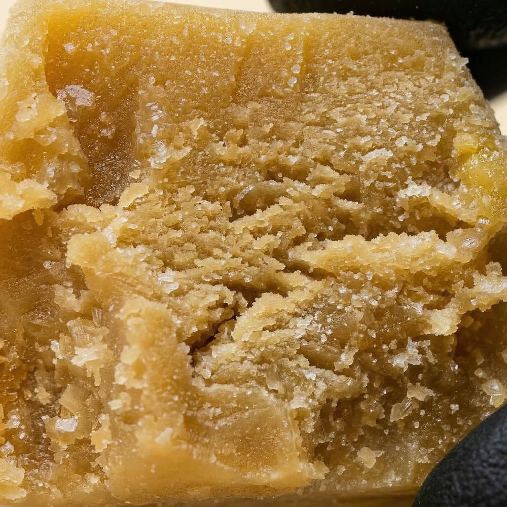 Gros plan détaillé sur la texture cristallisée et les trichomes riches en terpènes de la résine CBD Ice O Lator Mango - Maison Sativa.