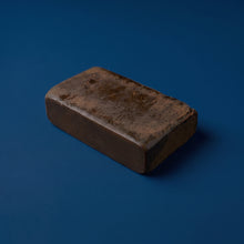 Bloc entier et compact de résine de canabise légale 3x filtré Maison Sativa sur fond bleu, illustrant la densité d'un hash issu d'un triple tamisage.
