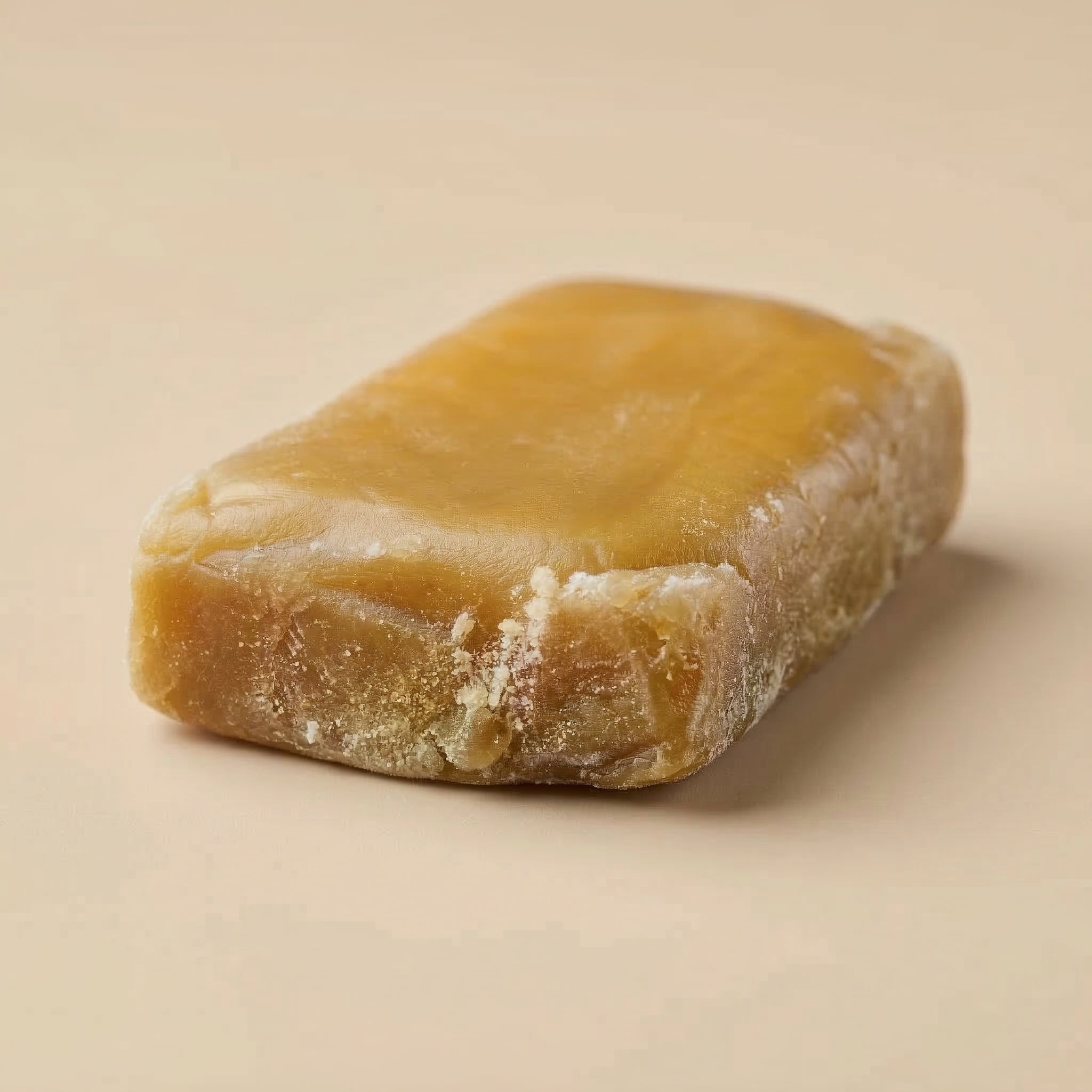 Bloc rectangulaire de résine de CBD haute qualité Ice O Lator Mango de la Maison Sativa posé sur un fond beige élégant.